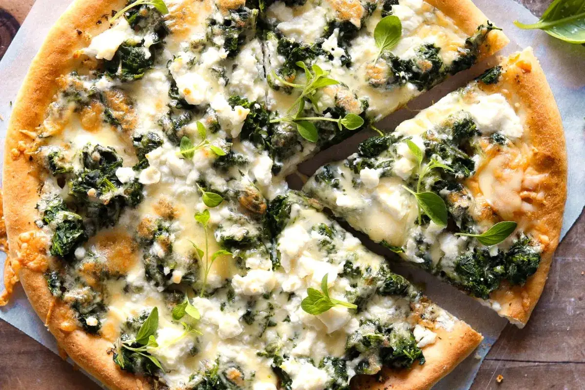 Pyszna pizza ze szpinakiem i serem feta, udekorowana świeżymi ziołami. Idealna na szybki obiad.