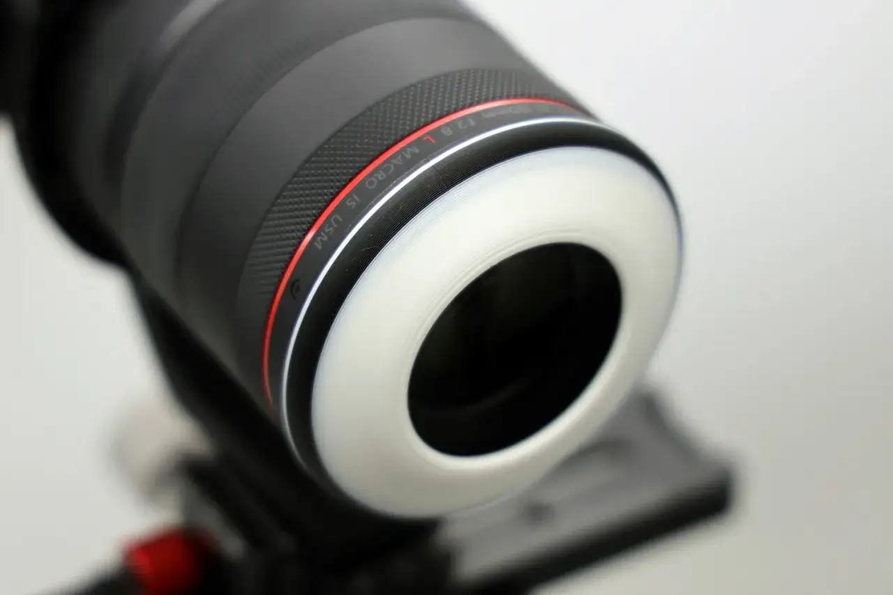 Gros plan d'un objectif macro 100mm f/2.8 L IS USM avec un diffuseur blanc. Ce photo détail révèle la texture de l'objectif.
