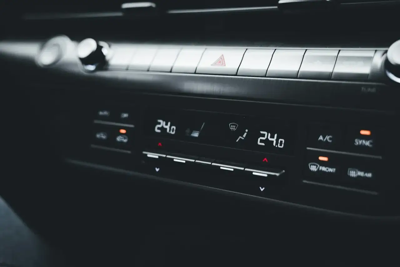 Panel klimatyzacji w samochodzie, wyświetlający 24 stopnie. Słychać ciche syczenie z klimatyzacji, gdy temperatura jest idealna.
