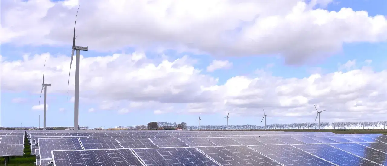 F&auml;lt med solceller och vindkraftverk under en molnig himmel. En vision f&ouml;r att kombinera solceller och vindkraft f&ouml;r en gr&ouml;nare framtid.
