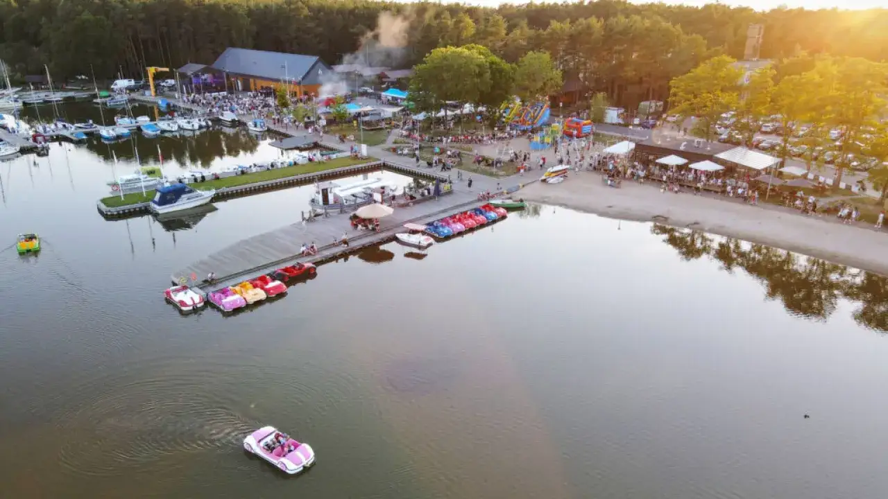 Dąbki atrakcje: kolorowe rowerki wodne, łodzie, plaża i mnóstwo ludzi bawiących się nad jeziorem.