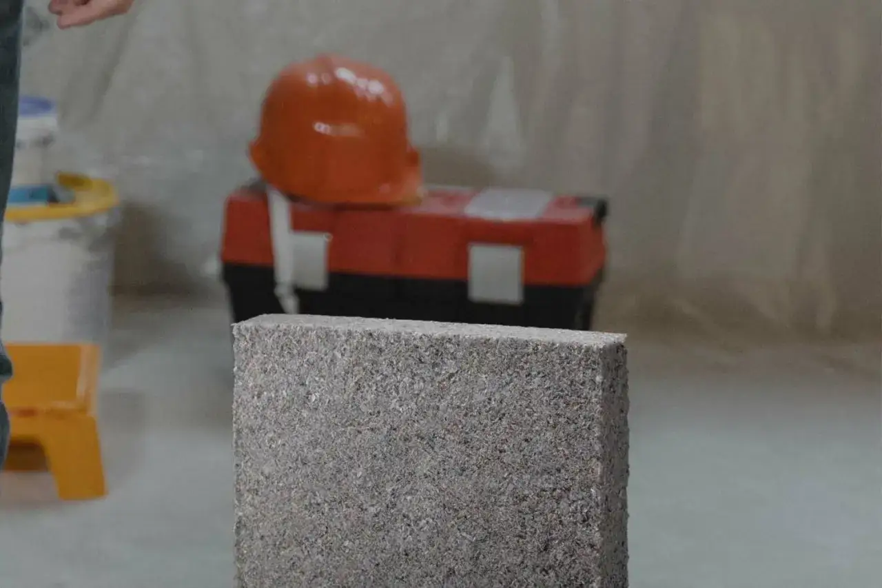Bloc de ouate de cellulose, un matériau d'isolation. Attention au danger potentiel lors de sa manipulation. Casque de chantier et boîte à outils en arrière-plan.