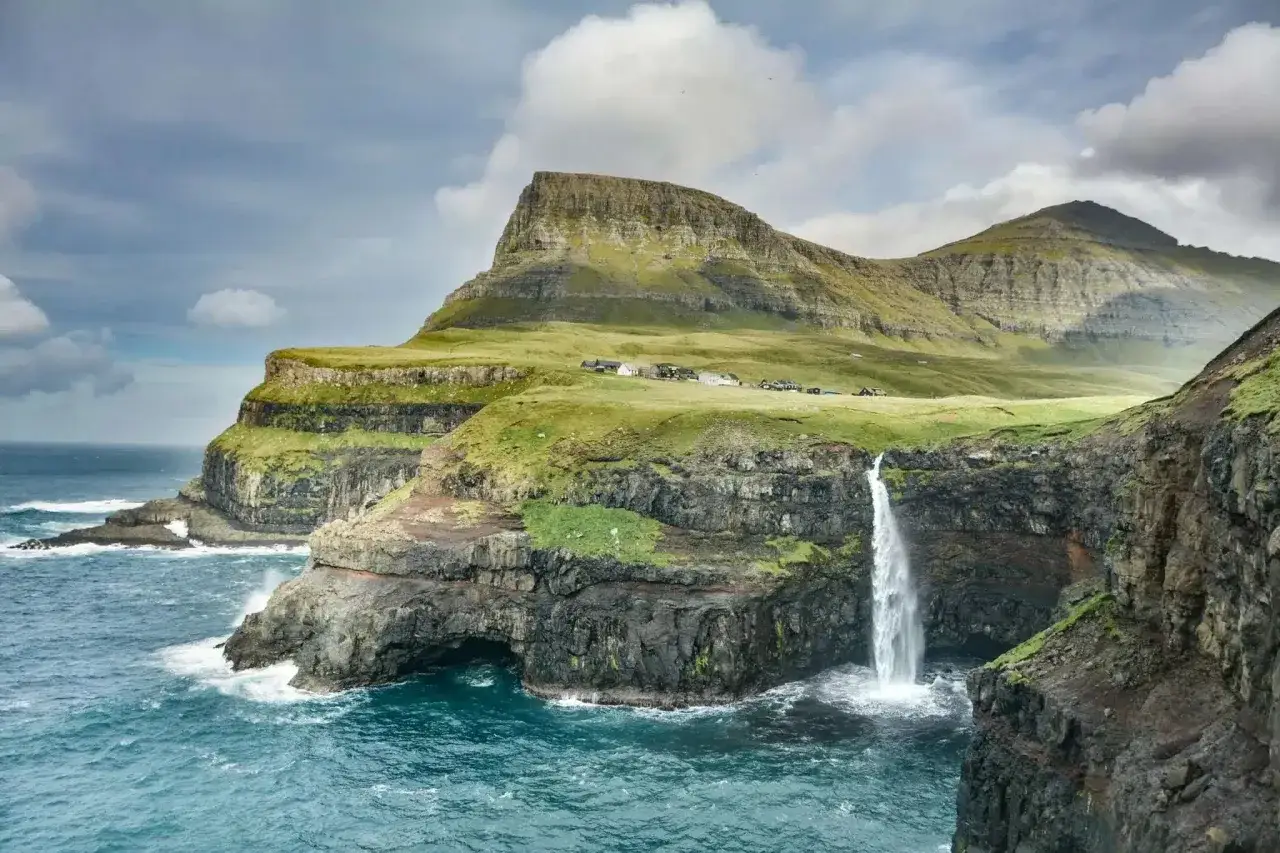 Gr&uuml;ne Klippen mit einem Wasserfall, der ins Meer st&uuml;rzt. Ein perfekter Ort, wo im Sommer reisen, um die Natur zu genie&szlig;en.