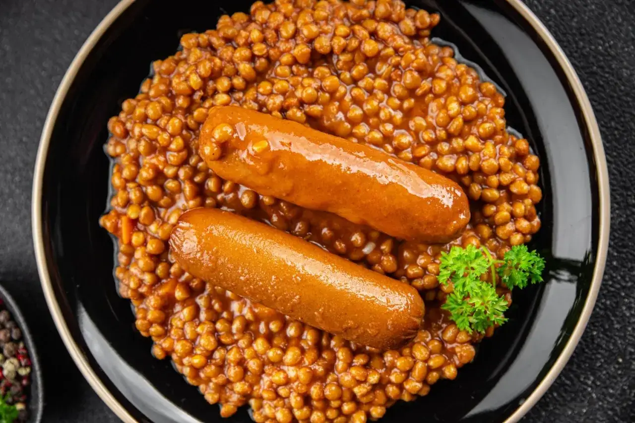 Saucisse lentille Cookeo : deux saucisses dorées sur un lit de lentilles savoureuses, garni de persil frais. Un plat réconfortant et facile à préparer.
