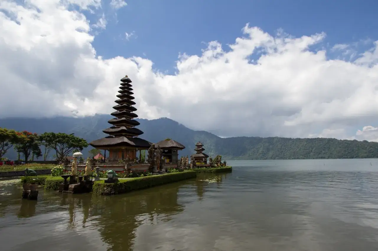 Temple Pura Ulun Danu Bratan sur le lac, une idée de que faire à Bali. Paysage serein avec montagnes en arrière-plan.