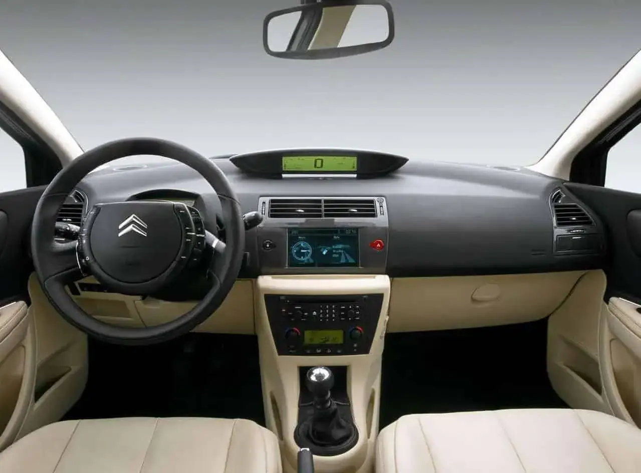 Wnętrze Citroena C4 2008 z kierownicą, cyfrowym wyświetlaczem i ekranem nawigacji.
