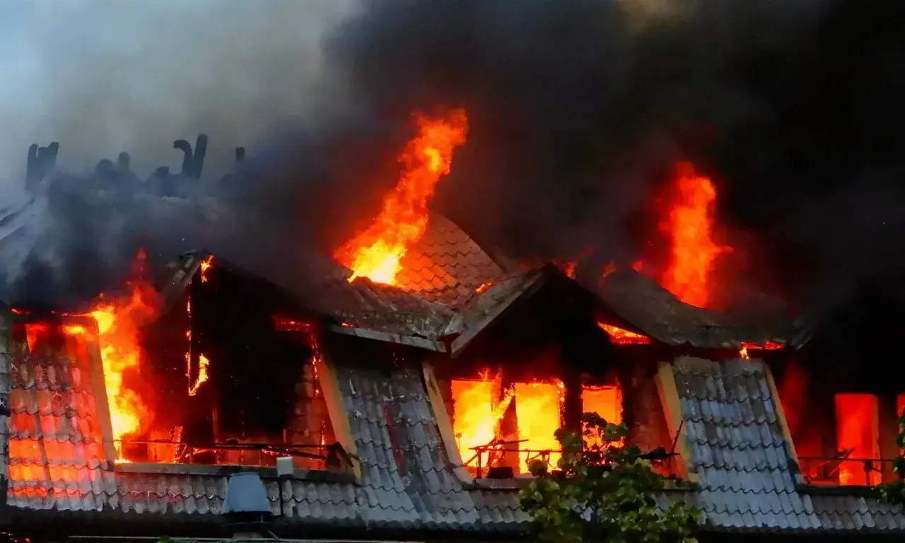 Płomienie trawią dach i okna budynku, unoszą się kłęby czarnego dymu. To przerażający przykład tego, czym jest pożar.