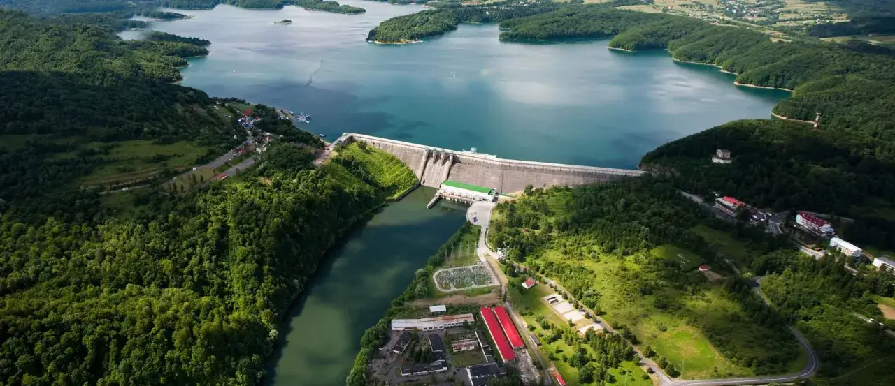 Majestatyczna solina zapora spiętrza turkusową wodę jeziora, otoczona bujnymi, zielonymi lasami.