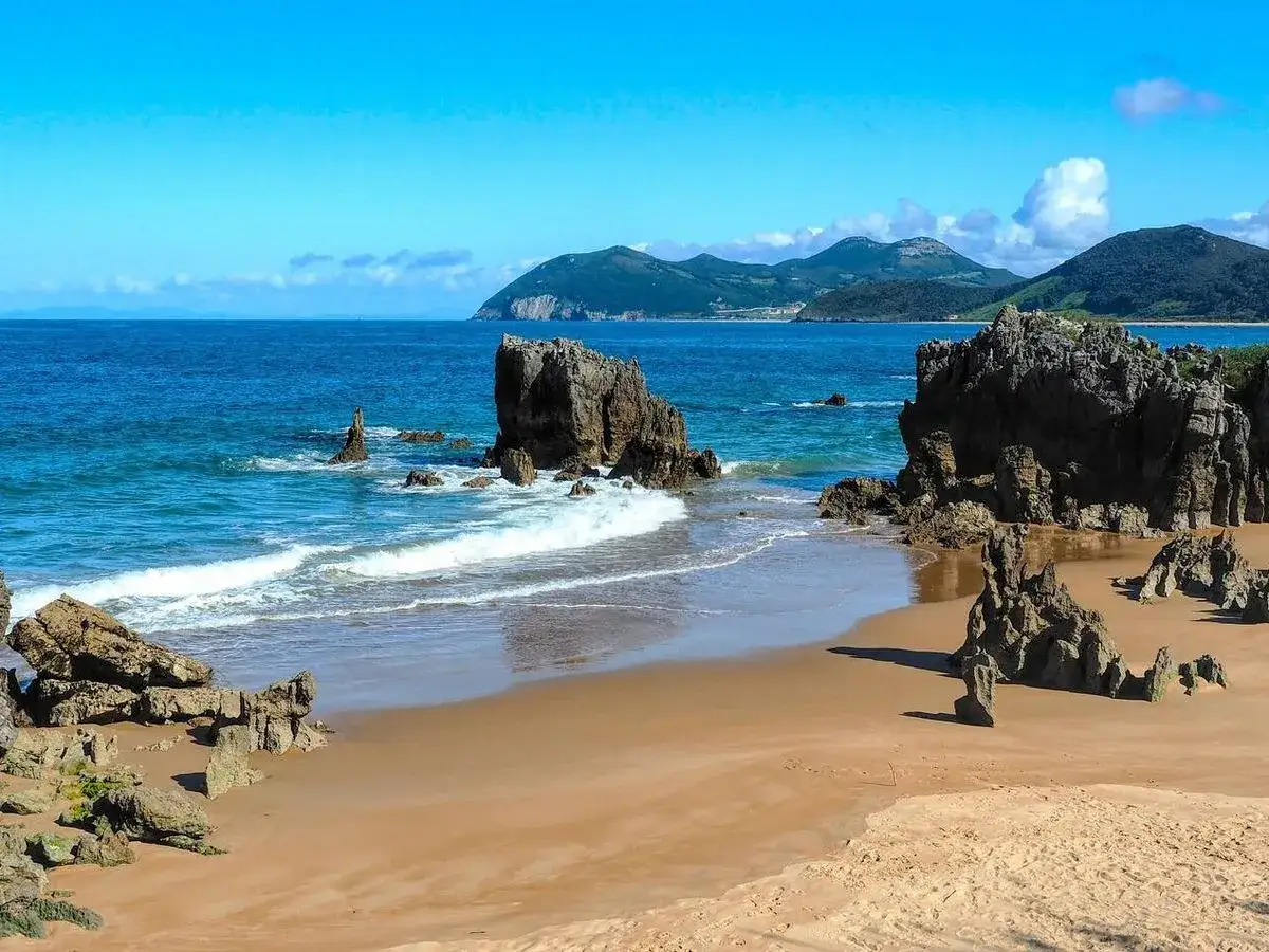 Playa de Arcisero, un lugar increíble que ver en Isla, Cantabria. Rocas y mar azul en un día soleado.