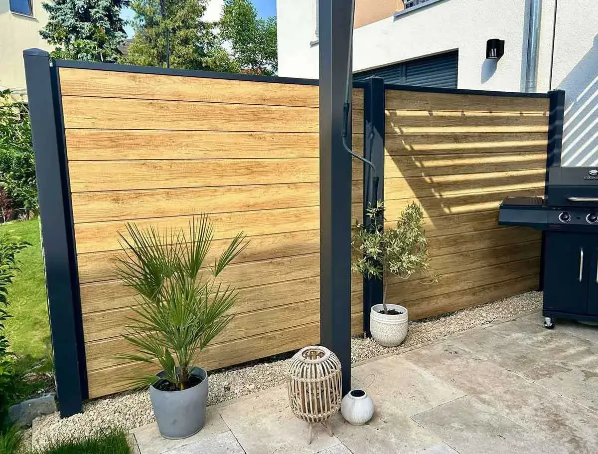 Moderner Sichtschutz aus Holz, ideal zum selber bauen. Eine Terrasse mit Grill und Pflanzen.