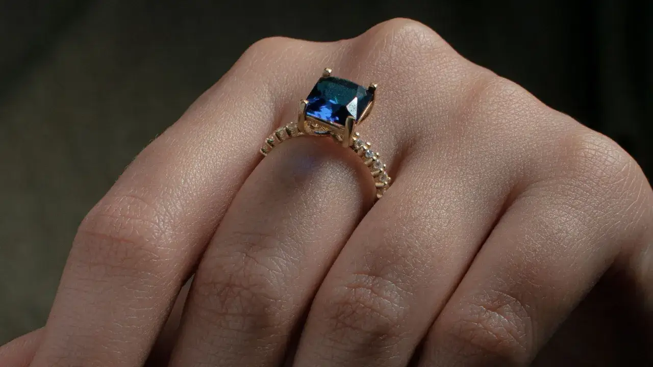 Anello d'oro con un magnifico zaffiro blu al centro, circondato da piccoli diamanti scintillanti.