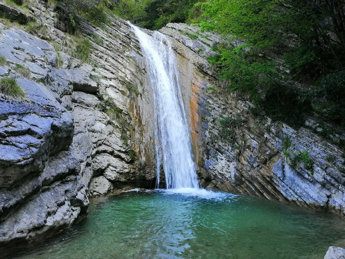 Cascate naturali con acqua cristallina che scende su rocce stratificate, un angolo segreto vicino al Lago di Garda.