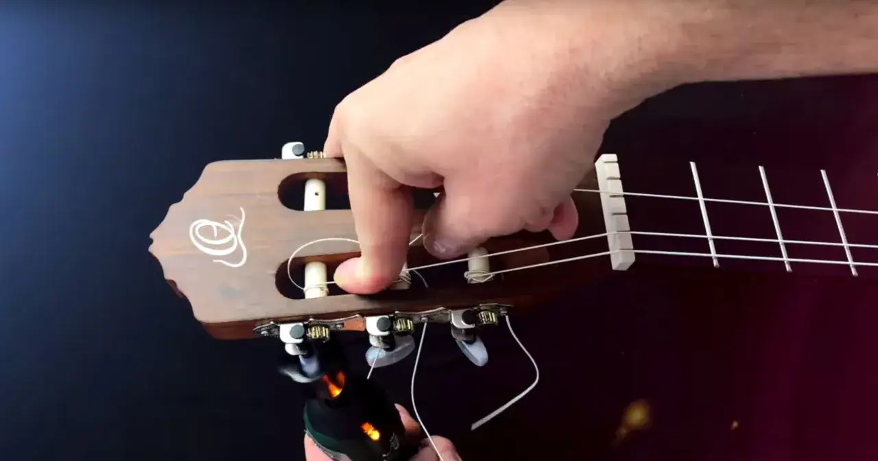 Dłoń naciąga nowe struny w gitarze, przygotowując ją do gry.