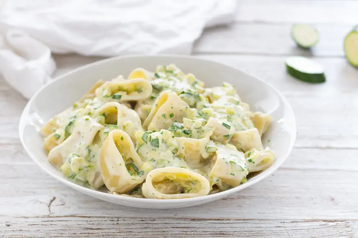 Piatto di pasta robiola e zucchine, cremoso e invitante, con pezzi di zucchine fresche e erbe aromatiche.