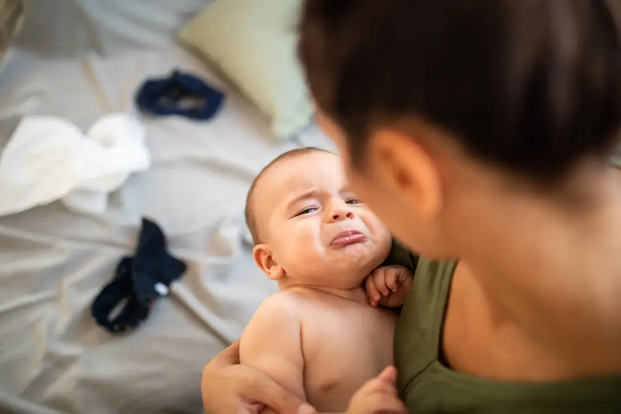 Maluch płacze, bo dziecko spadło z łóżka. Mama go przytula, próbując uspokoić.