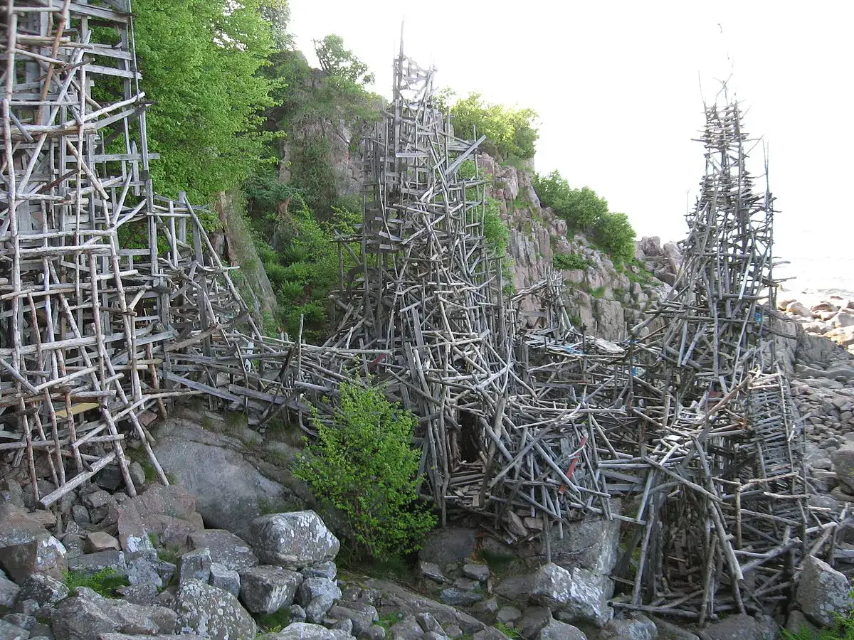 Lars Vilks Nimis, en skulptur av drivved och tr&auml;, reser sig mot en klippig kust.
