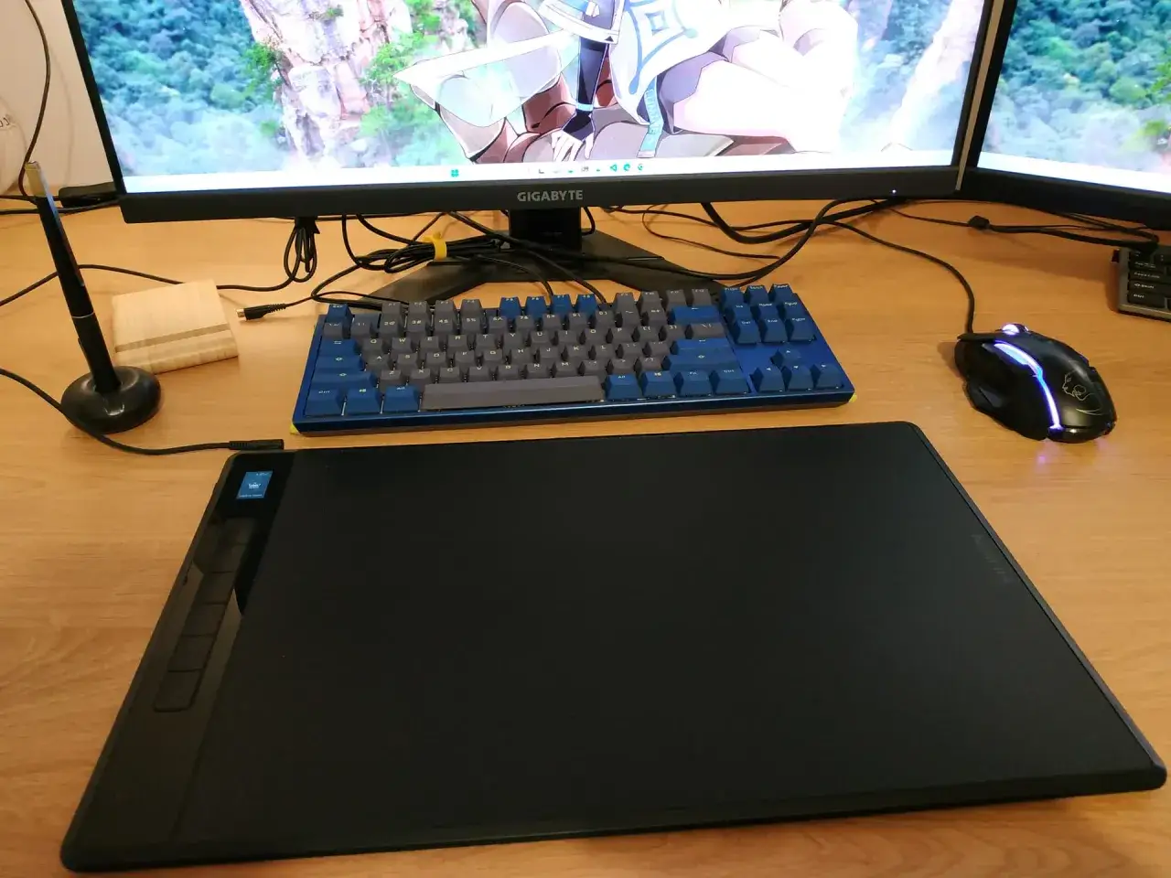 Stanowisko do pracy z komputerem: tablet graficzny, klawiatura, myszka i monitor z grafiką. Idealne miejsce na rozpoczęcie nauki digital painting kurs.