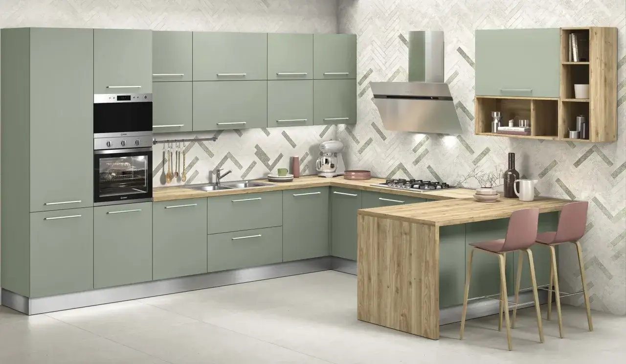 Elegante cucina verde malva con isola in legno, elettrodomestici moderni e sgabelli rosa.