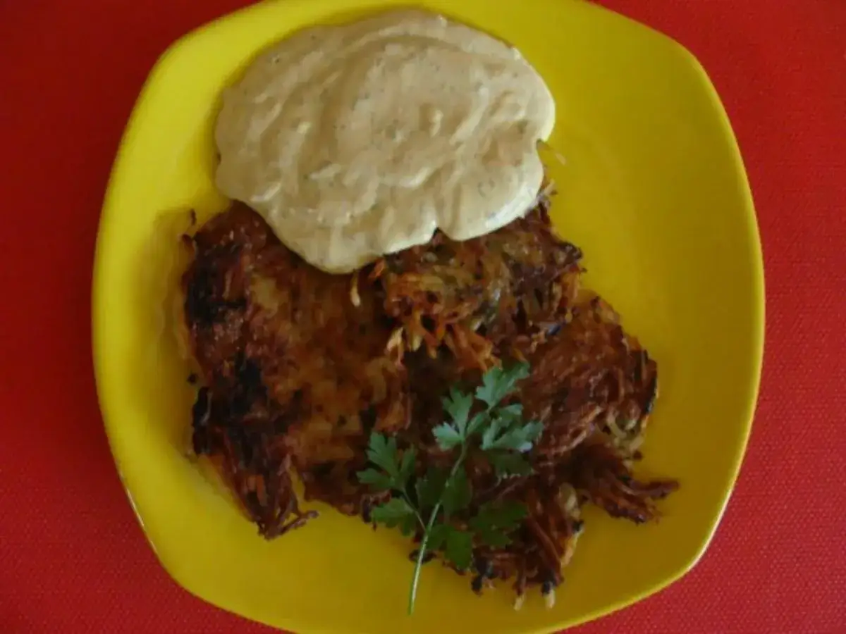 Omas Kartoffelpuffer Rezept: goldbraune Reibekuchen aus gekochten Kartoffeln mit Kr&auml;uterquark und Petersilie auf gelbem Teller.