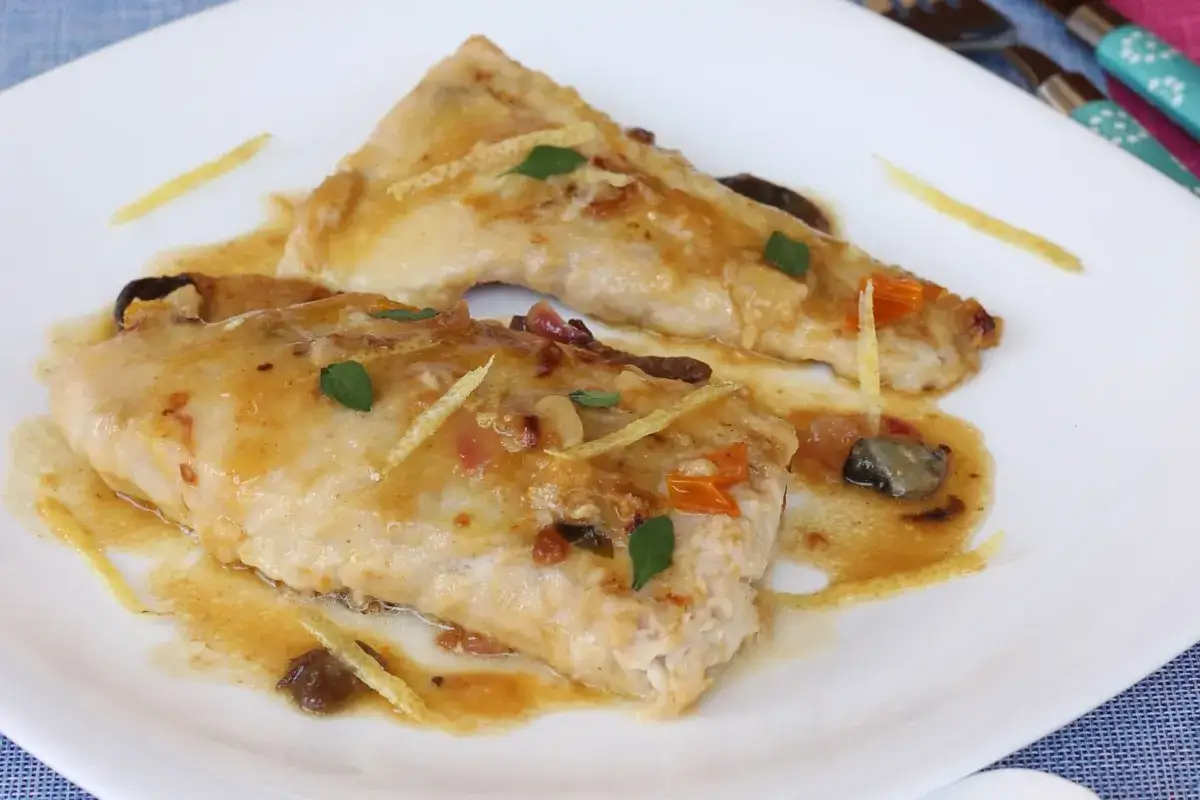 Delizioso pesce persico in padella al limone, con scorzette e erbe aromatiche. Una ricetta semplice e gustosa.