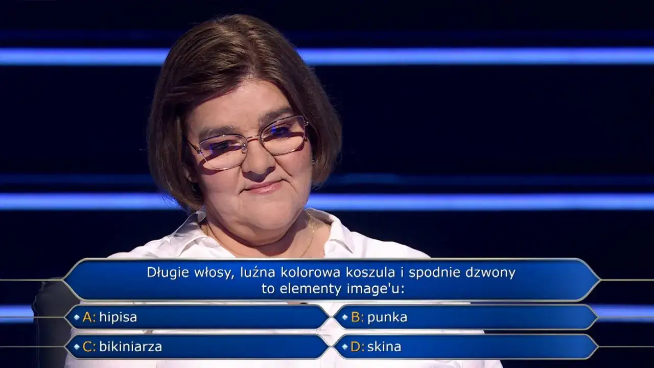 Kobieta w okularach, w białej koszuli, zastanawia się nad pytaniem z teleturnieju