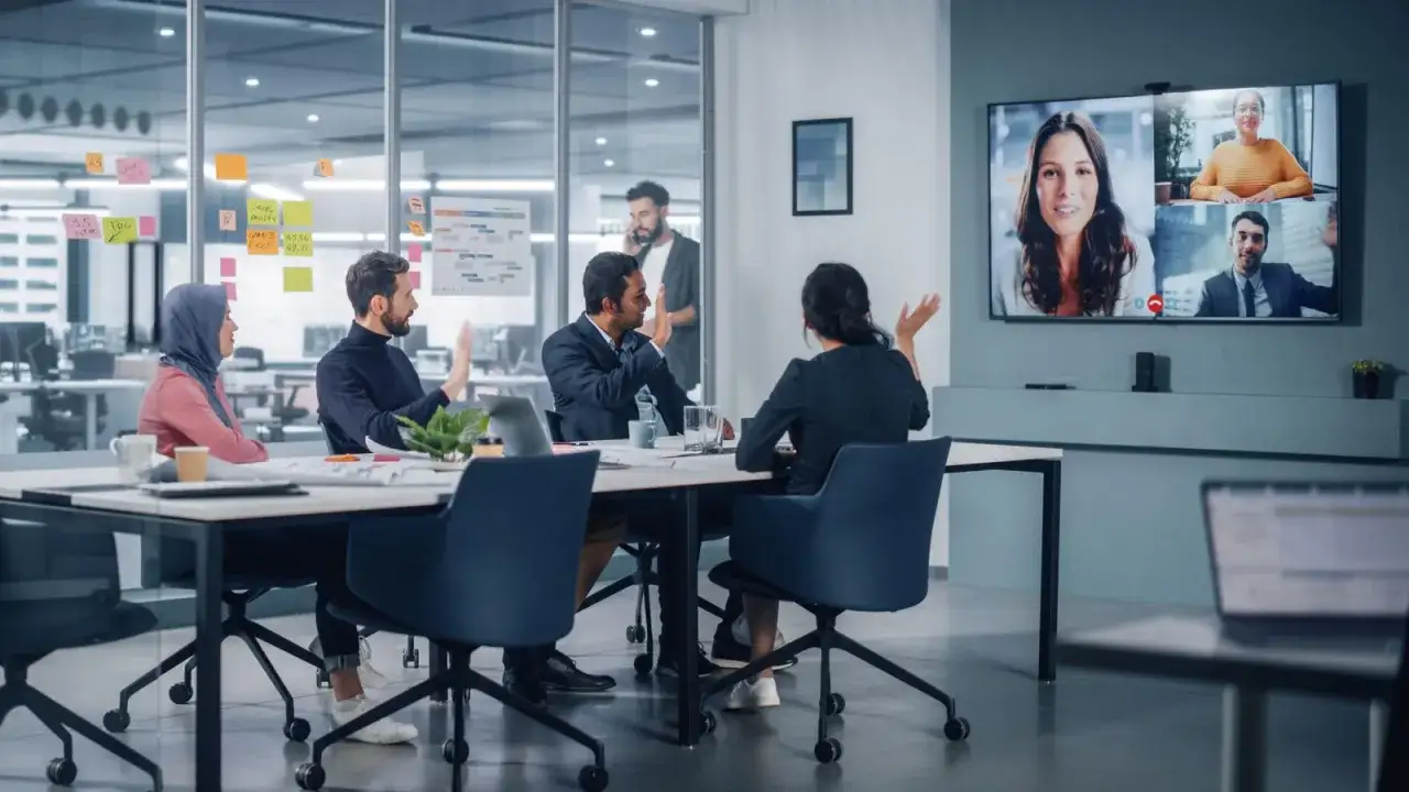 Teamm&ouml;te med hybridl&ouml;sning. En policy f&ouml;r distansarbete diskuteras medan kollegor deltar via videokonferens p&aring; stor sk&auml;rm.