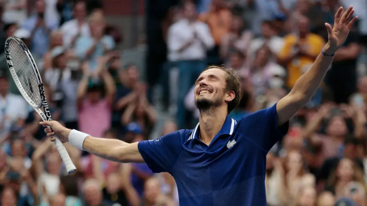 Daniil Medvedev celebra una victoria, con la raqueta en alto y los brazos extendidos, tras un gran torneo de Grand Slam.