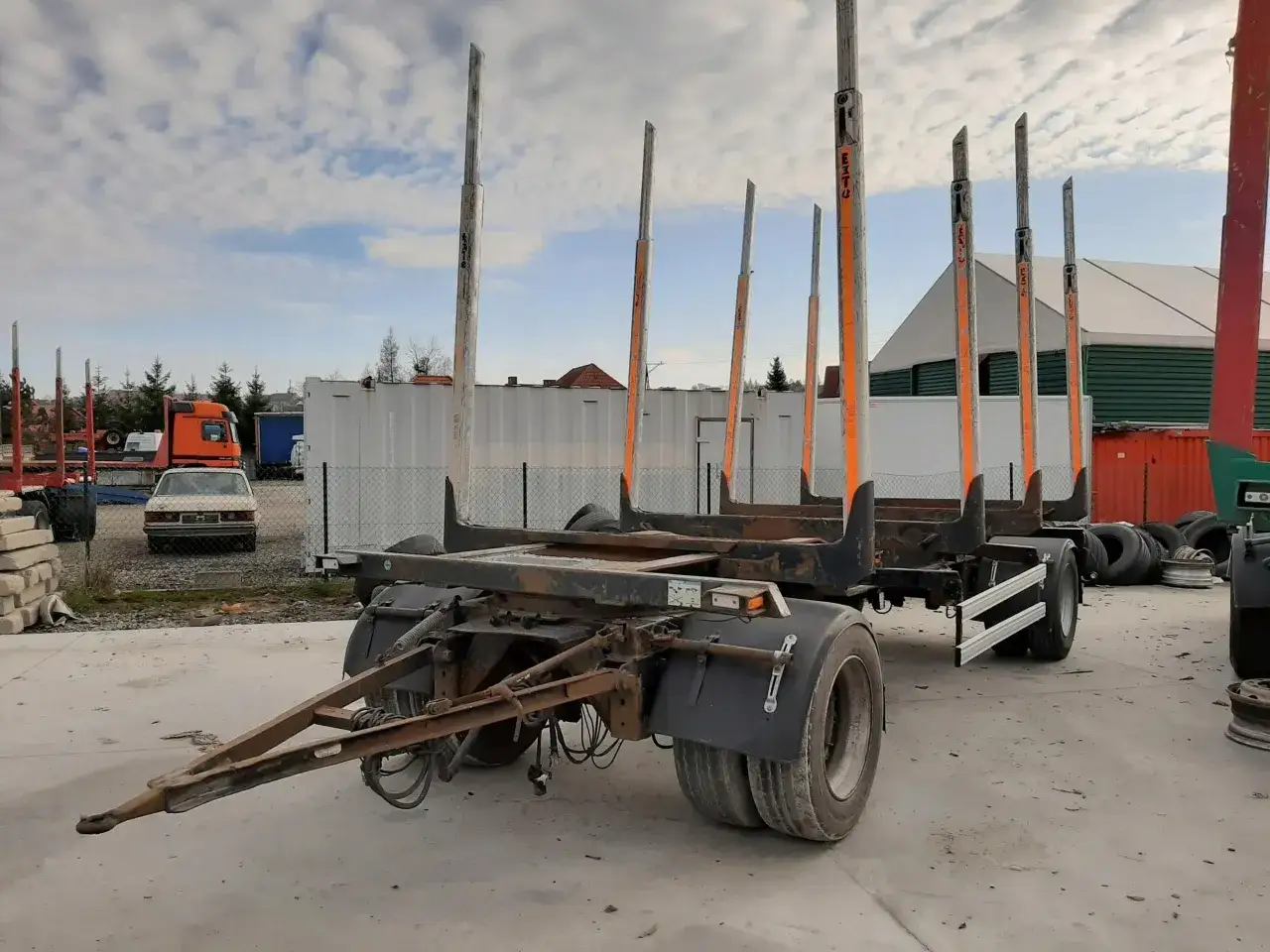 Przyczepa do transportu drewna z wysokimi słupkami, gotowa do załadunku.