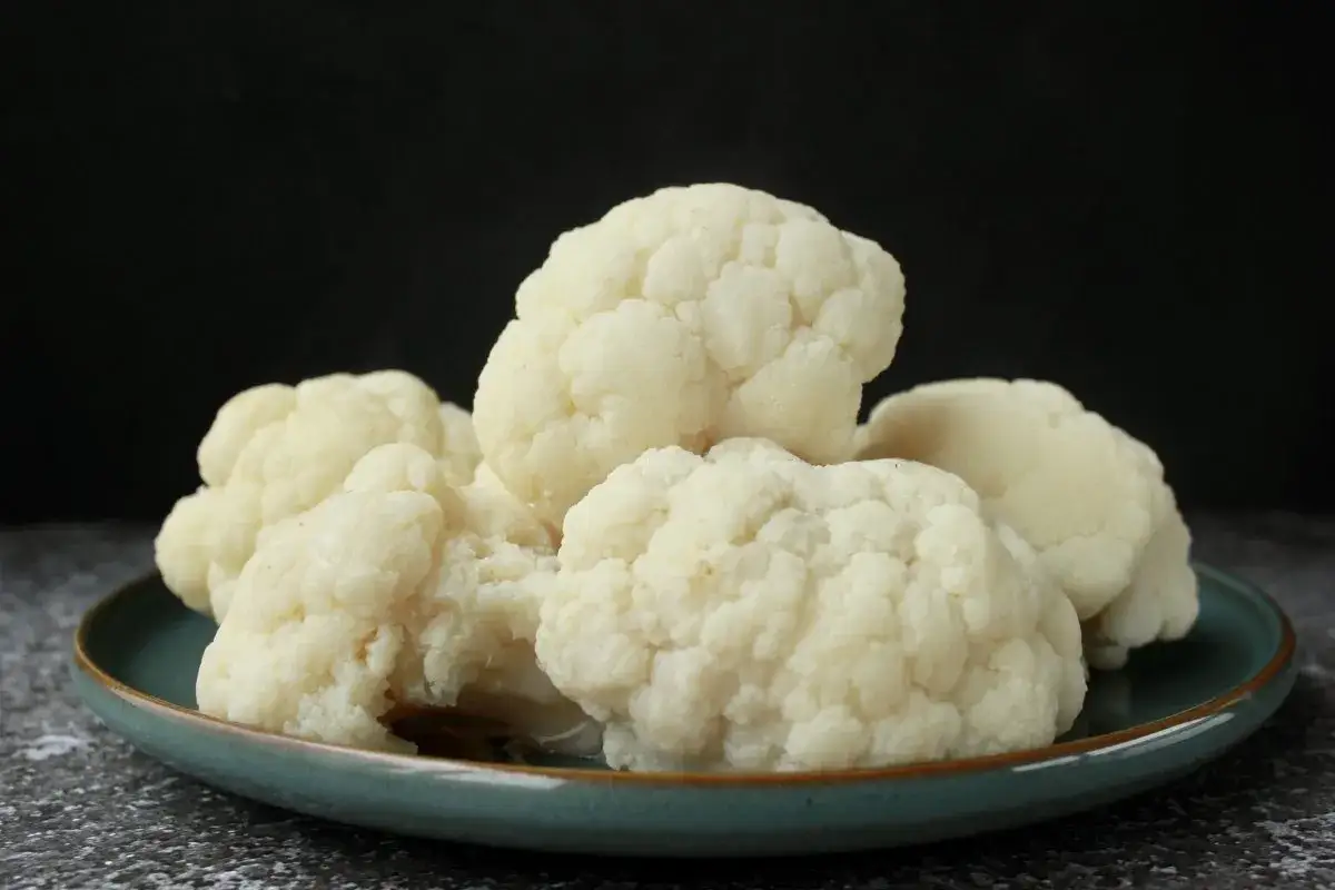Montón de coliflor cocida en un plato verde. Ideal para una receta saludable.
