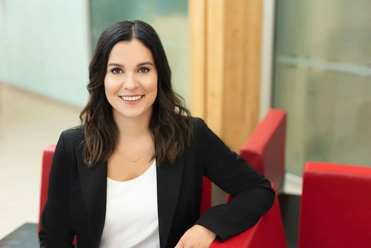Une femme souriante, en veste noire, dans un cadre moderne. Une photo corporate qui inspire confiance.