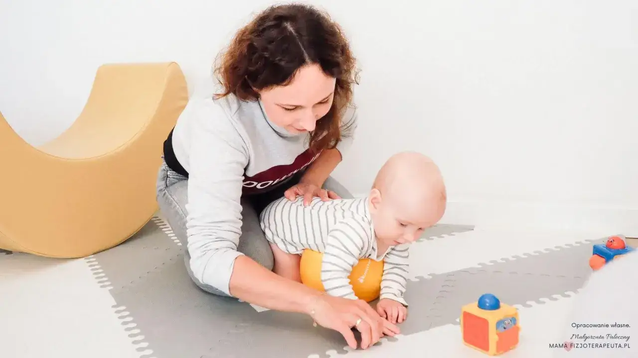Mama wspiera 5-miesięczne dziecko w nauce raczkowania. Maluch na pomarańczowej poduszce, gotowy do ruchu.