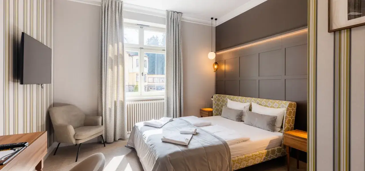 Elegancki apartament suite, co to znaczy? To przestronne, komfortowe wnętrze z dużym łóżkiem, wygodnym fotelem i widokiem na miasto.