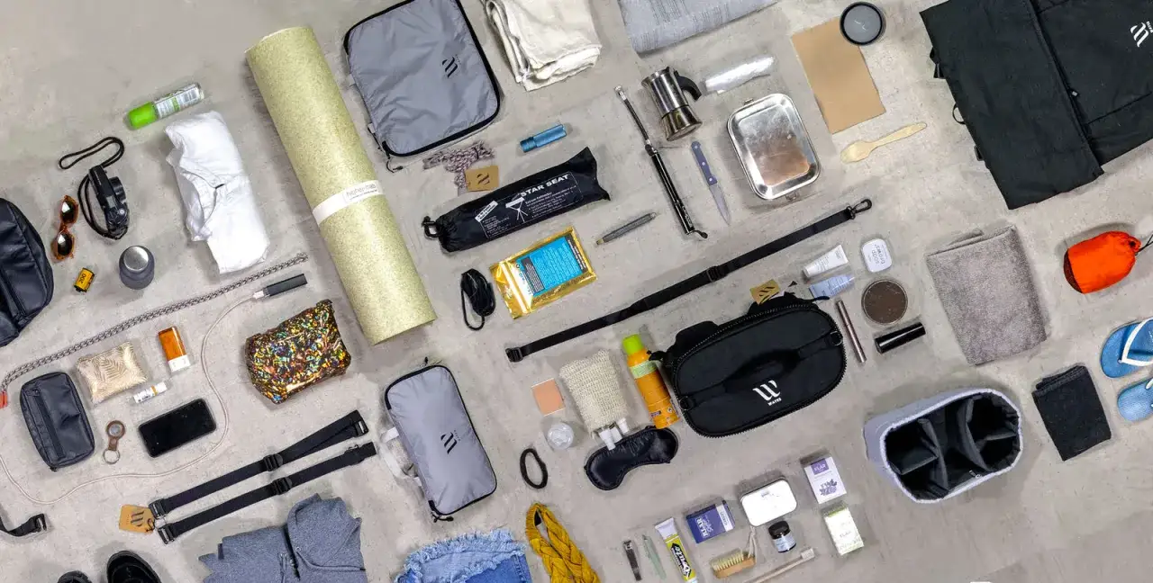 Festival essentials laid out: a portable seat, toiletries, a camera, sunglasses, a phone, and a change of clothes.