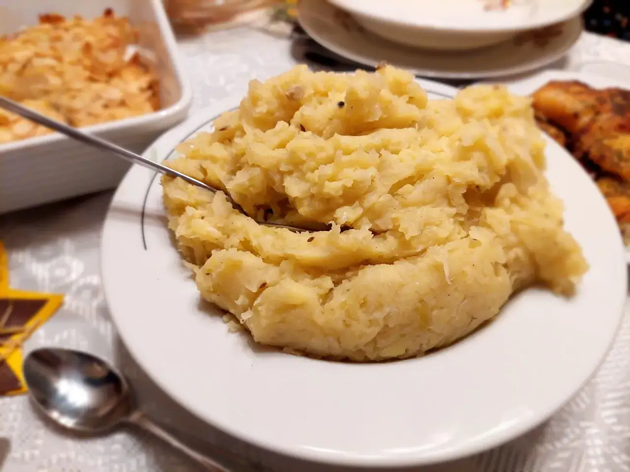 Panczkraut, czyli pyszne puree ziemniaczane z dodatkami, czeka na widelcu. Obok pieczone mięso i zapiekanka.