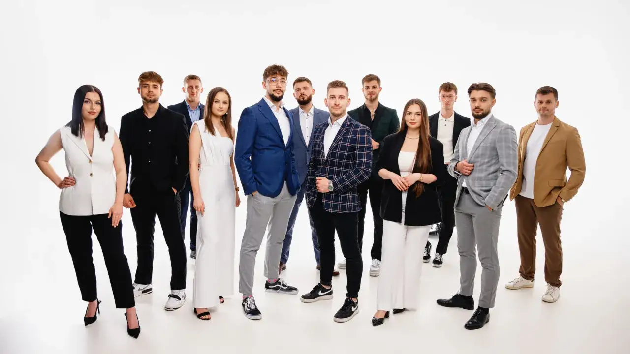 Profesjonalny zespół, który wie, jak prowadzić biuro nieruchomości. Elegancko ubrani ludzie pozują do zdjęcia.