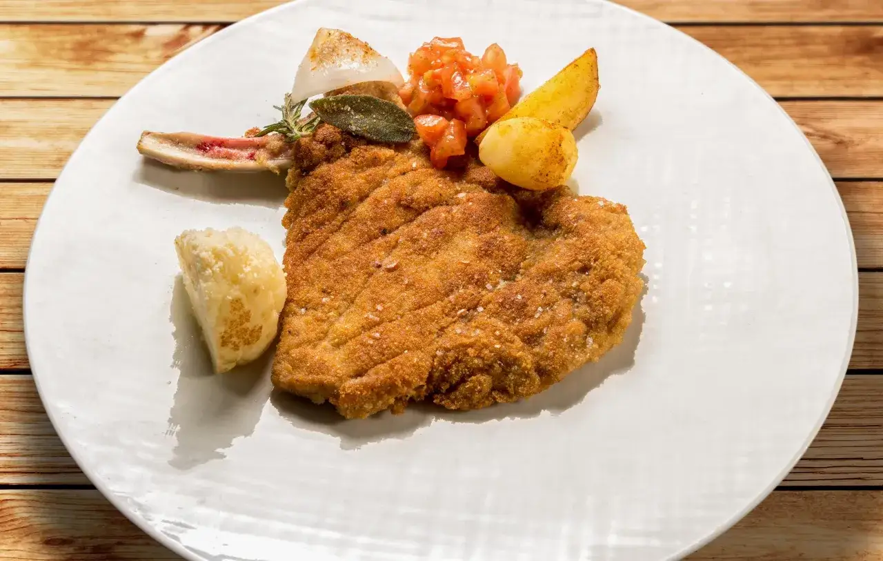 Cotoletta alla milanese croccante con patate e pomodoro. Un classico da provare per scoprire cosa mangiare a Milano.