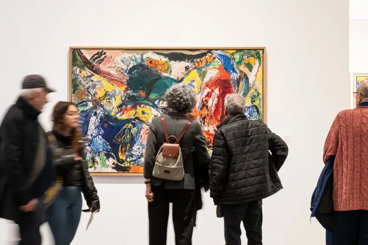 Visitantes observan una vibrante pintura abstracta en una de las exposiciones en Valencia.