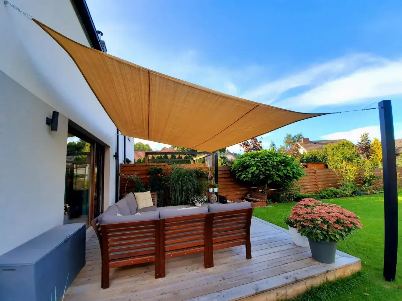 Une terrasse aménagée avec un salon de jardin confortable sous un voile d'ombrage. Parfait pour profiter du soleil en toute sérénité.