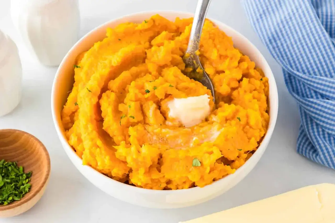 Un cremoso puré de boniato, con un trozo de mantequilla derritiéndose y espolvoreado con perejil fresco.