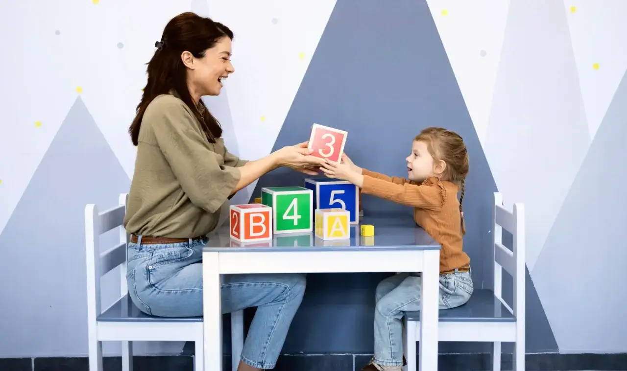 Une femme et une enfant jouent avec des cubes numérotés. Une scène qui illustre parfaitement le master psychopédagogie à distance.