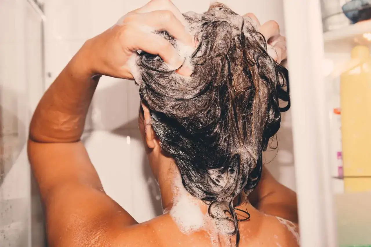 Hände massieren Schaum ins nasse Haar. Ein entspannender Moment beim Haare waschen.