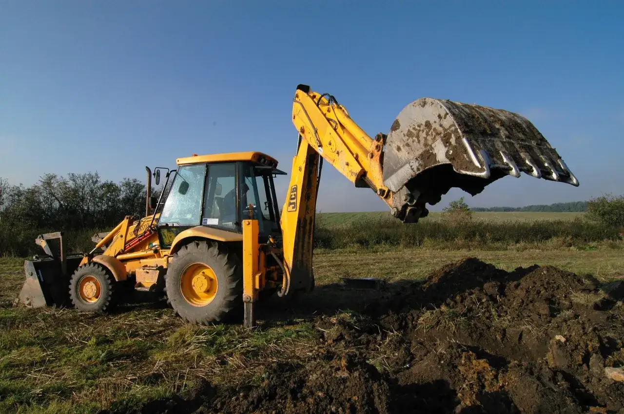 Koparka wykonuje wykop pod ławy fundamentowe, odsłaniając ziemię.