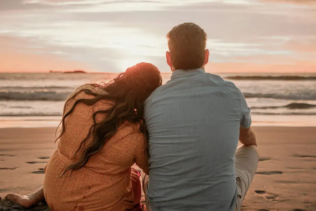 Coppia abbracciata sulla spiaggia al tramonto, un momento di pura magia tra i **posti romantici Italia**.