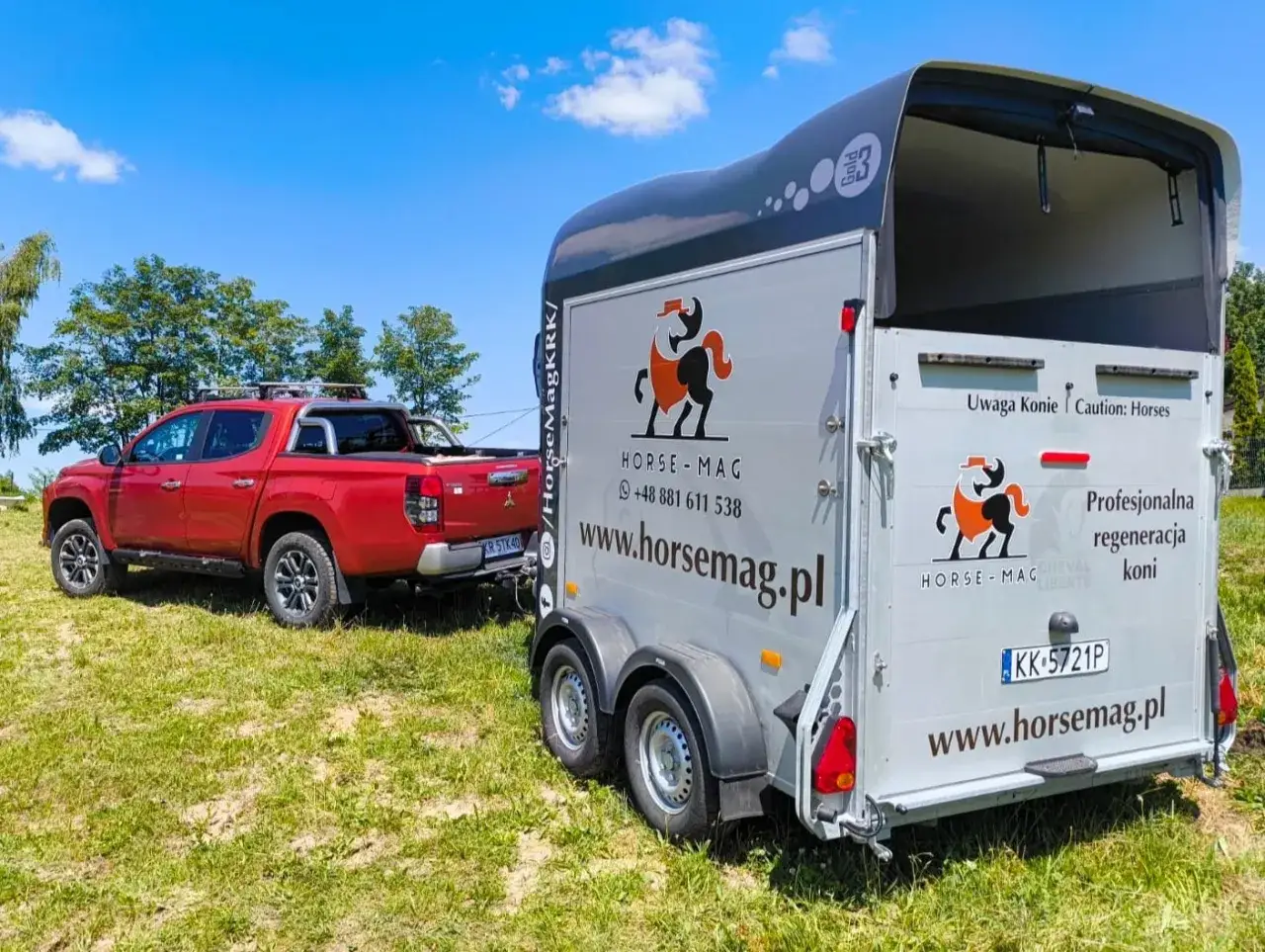 Czerwony pickup holuje przyczepę do przewozu koni. Na przyczepie logo HORSE-MAG i napis 