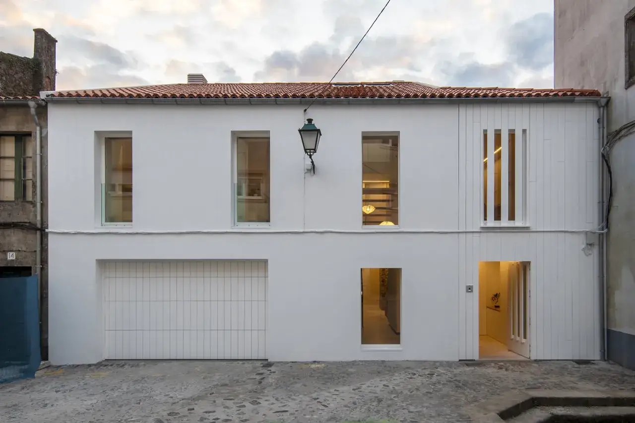 Fachada moderna con pintura al pliolite, puerta de garaje, ventanas y entrada iluminada.