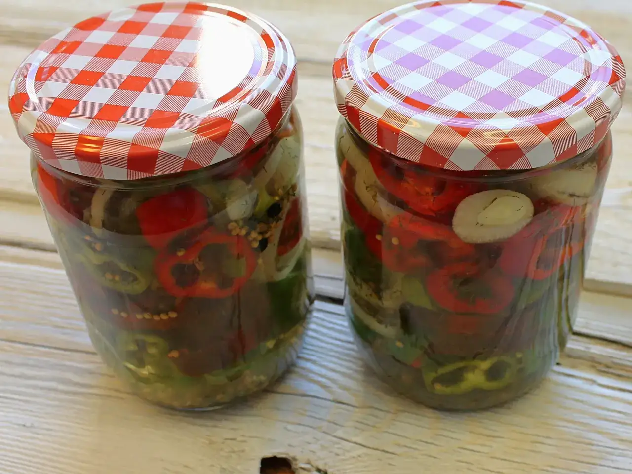 Zwei Gläser mit eingelegten Chilis und Zwiebeln, bereit zum Genießen.