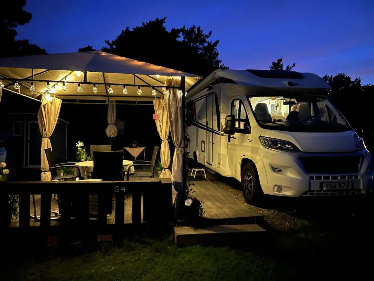 Kv&auml;llsst&auml;mning p&aring; Marholmen camping med husbil parkerad vid ett upplyst lusthus.