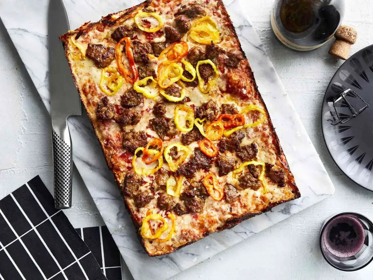 Prostokątna pizza z kawałkami kiełbasy i plasterkami papryczki, idealne składniki na pizzę.