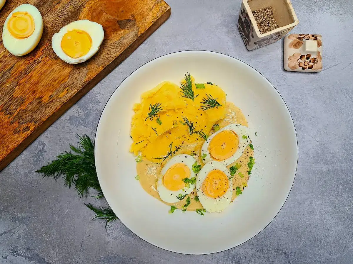 Pyszne jajka w sosie musztardowym z puree ziemniaczanym, udekorowane koperkiem i szczypiorkiem. Idealne na obiad.