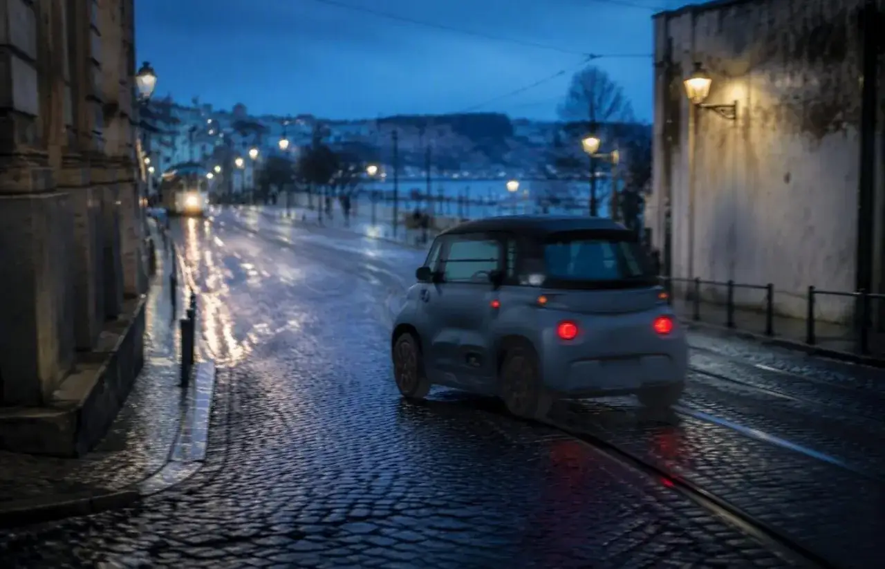 Citroën Ami, agile e compatta, sfreccia su strade bagnate al crepuscolo. Le sue prestazioni urbane brillano anche con poca luce.